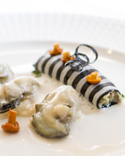Rohe und gekochte Auster an weißem und schwarzem Tintenfisch mit Chablis Weine